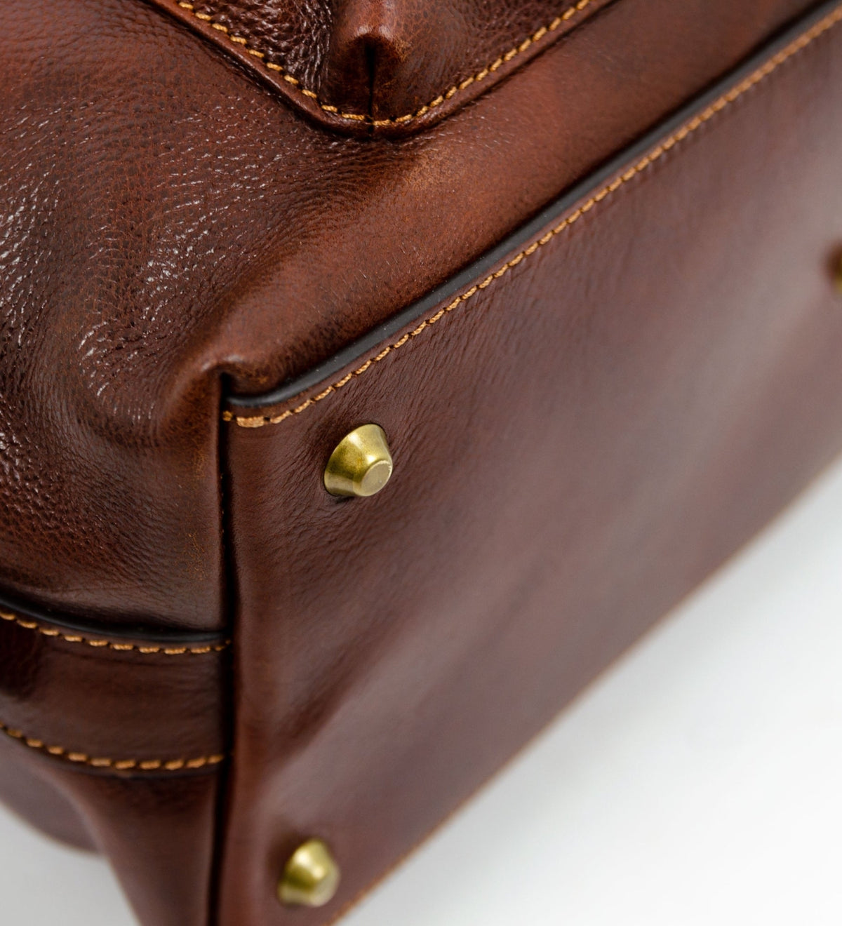 Brass studs on the base corner of the brown East of Eden leather bag