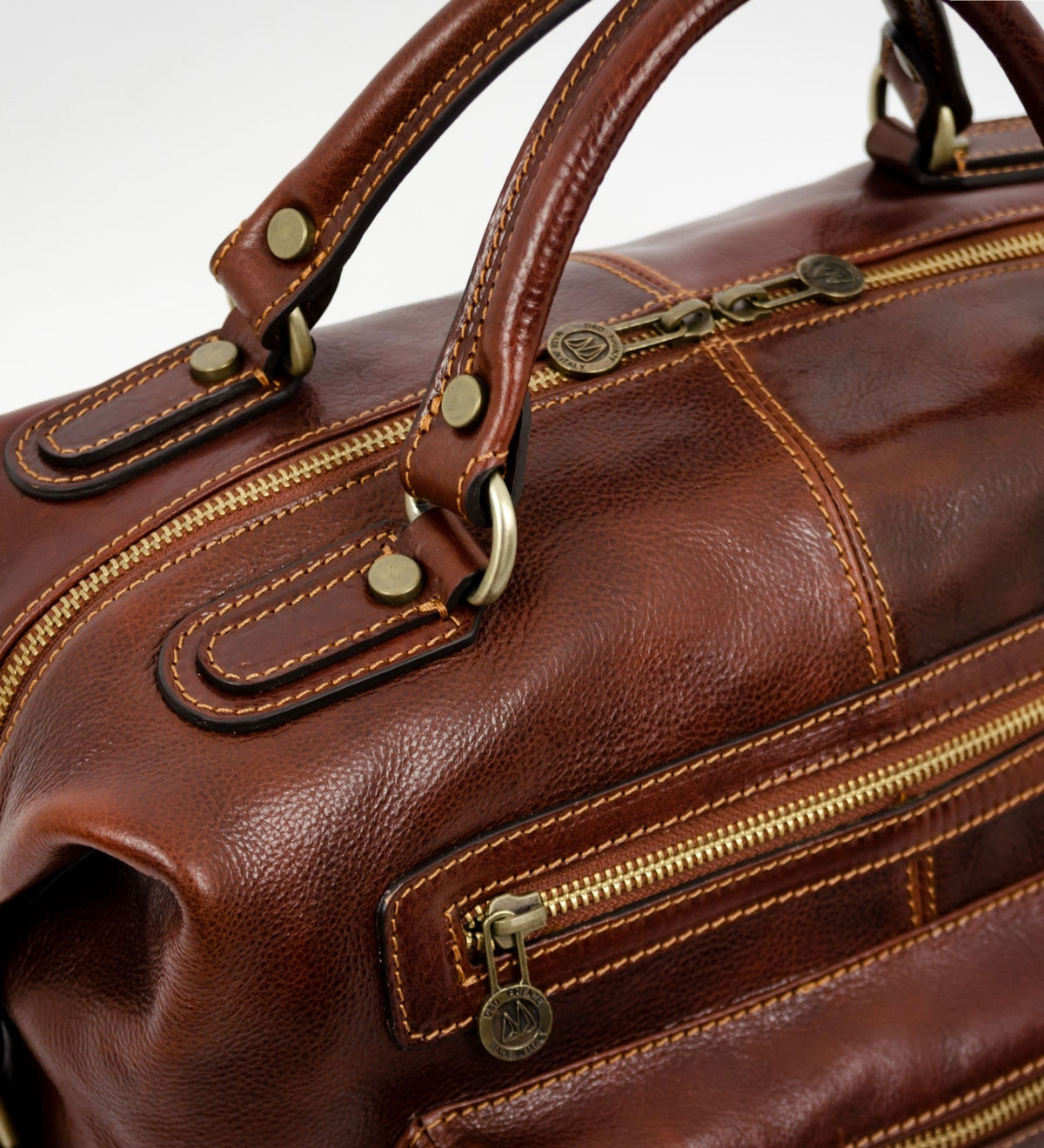 Close-up of the top handle and brass zipper pull on the brown East of Eden leather bag